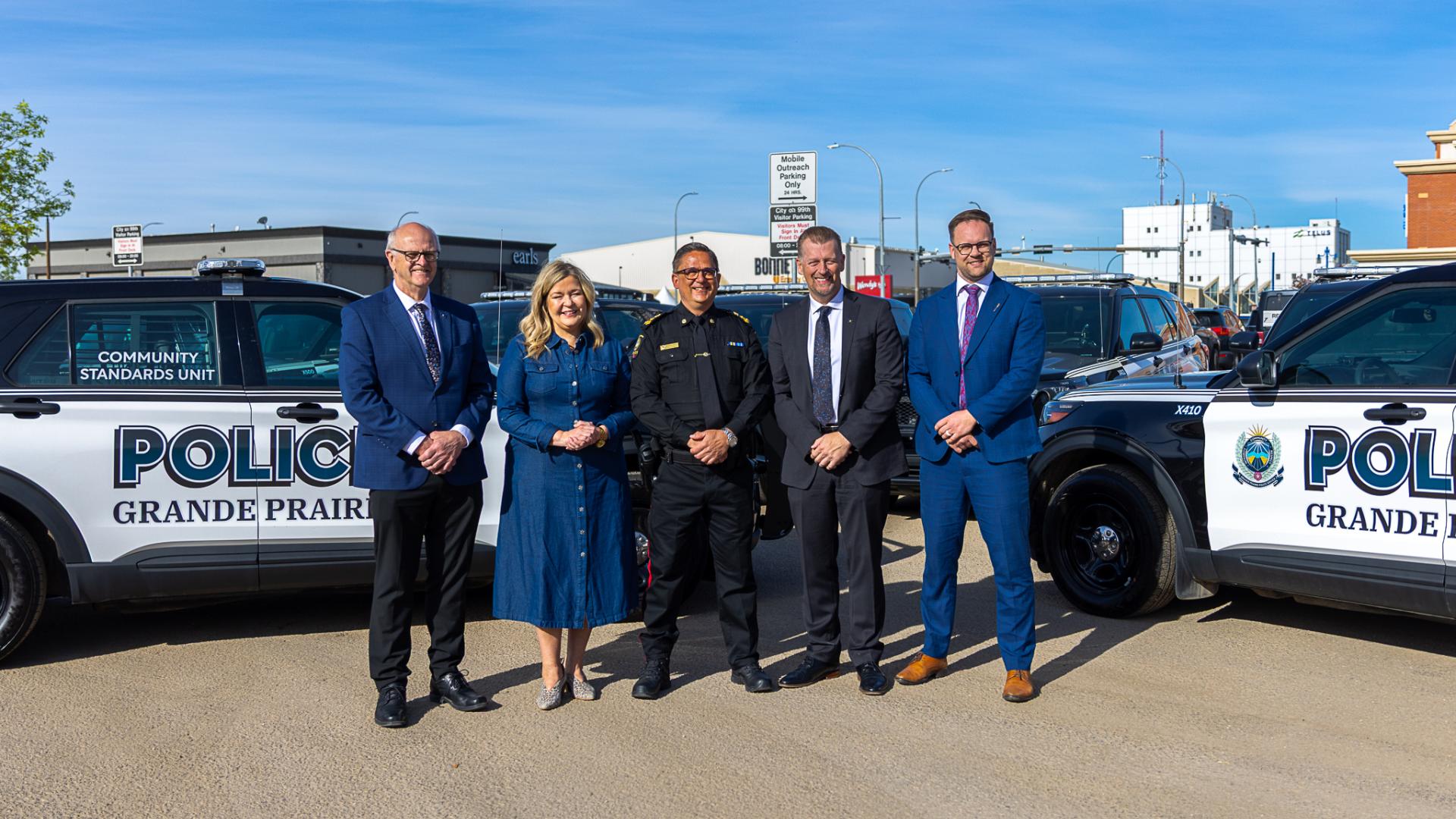 Grande Prairie - Wapiti MLA Ron Wiebe, City of Grande Prairie Mayor Jackie Clayton, Grande Prairie Police Service Chief of Police Dwayne Lakusta, Minister of Public Safety and Emergency Services Mike Ellis, and Grande Prairie MLA Nolan Dyck stand in front of GPPS cruisers. 