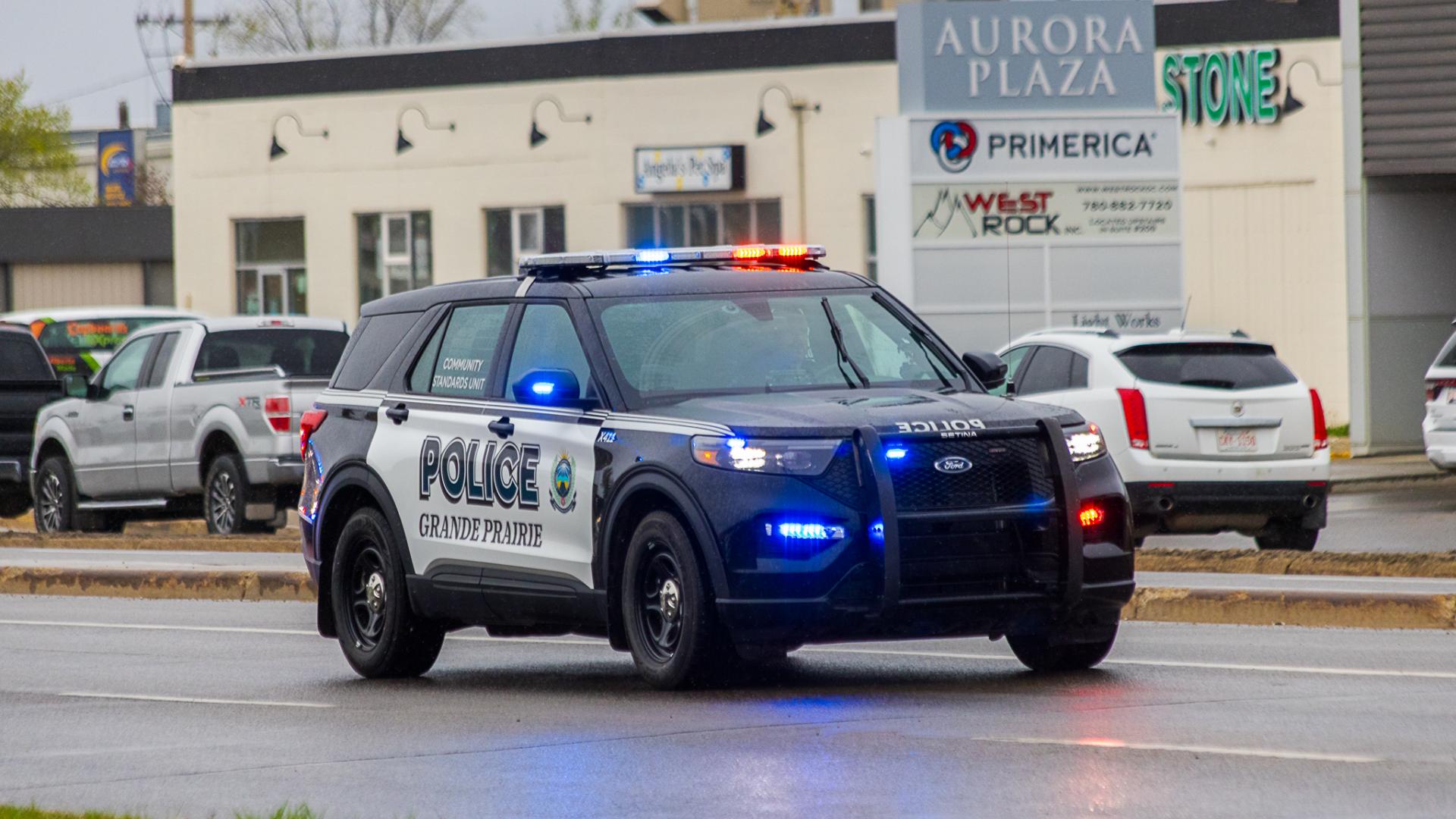 A Grande Prairie Police Service vehicle drives in the rain with its lights on.
