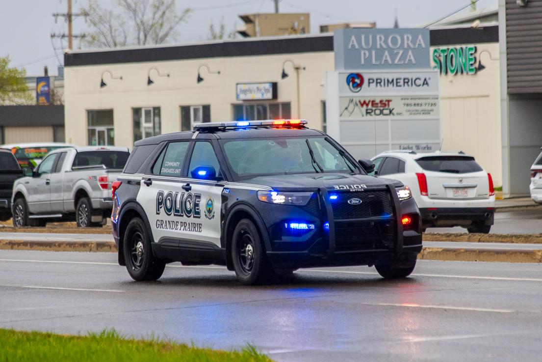 A Grande Prairie Police Service vehicle drives in the rain with its lights on.
